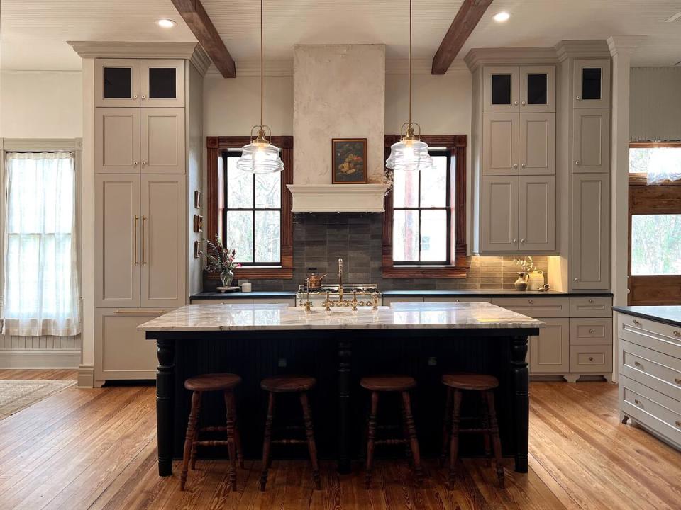 A kitchen by MaCenna Lee mixes powdery tones of gray with richly hued woods and bronze finishes