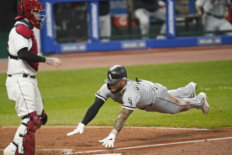 Chicago White Sox's Yoan Moncada, right, scores as Cleveland Indians' Roberto Perez stands near the plate during the seventh inning of a baseball game Thursday, Sept. 24, 2020, in Cleveland. (AP Photo/Tony Dejak)