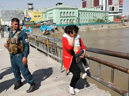 An Afghan woman carries a child rescued from the building of Ministry of Communication and Information Technology in Kabul, Afghanistan April 20, 2019. REUTERS/Mohammad Ismail