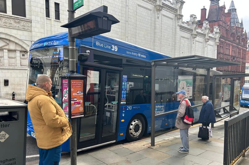 39 Blue Line single decker bus pulling up to bus stop on Queen Street, Nottingham, with passengers waiting outside