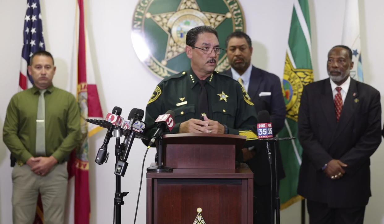 Sheriff Billy Woods at the microphone, with three officials standing behind him.