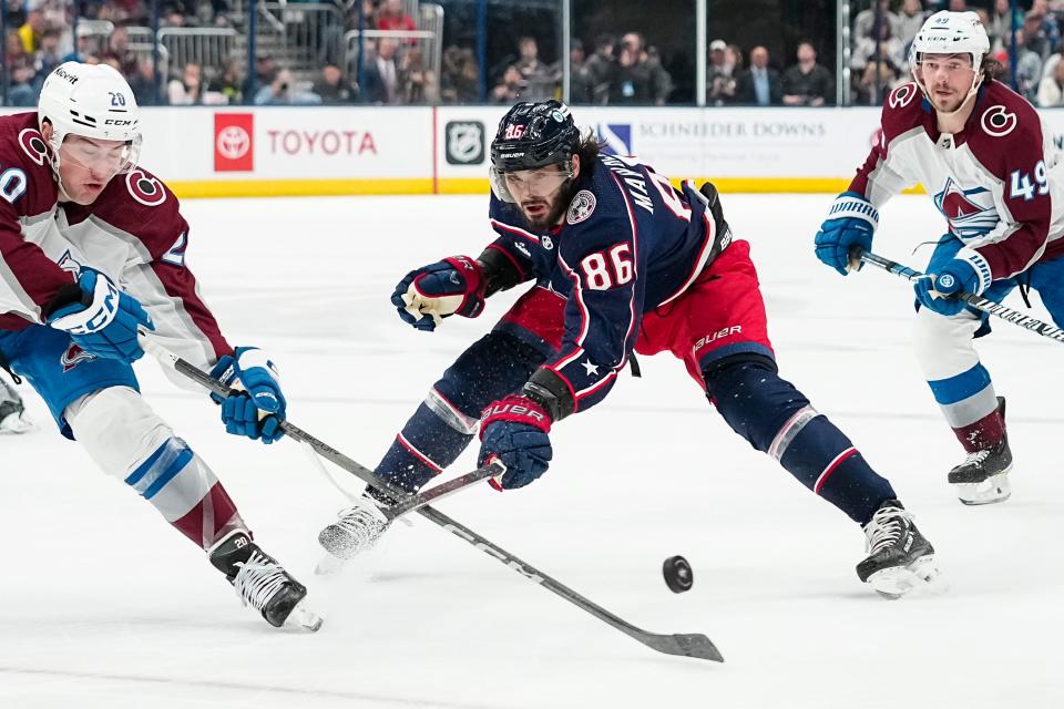 Apr 1, 2024; Columbus, Ohio, USA; Columbus Blue Jackets right wing Kirill Marchenko (86) skates between Colorado Avalanche center Ross Colton (20) and defenseman Samuel Girard (49) during the first period of the NHL hockey game at Nationwide Arena.