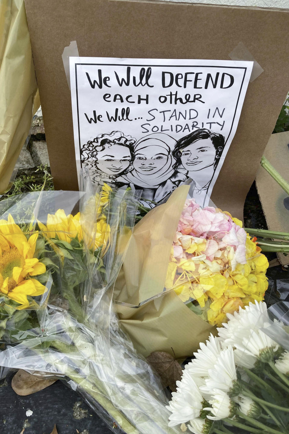 Flowers, candles and signs are displayed at a makeshift memorial on Friday, March 19, 2021, in Atlanta. Robert Aaron Long, a white man, is accused of killing several people, most of whom were of Asian descent, at massage parlors in the Atlanta area. (AP Photo/Candice Choi)