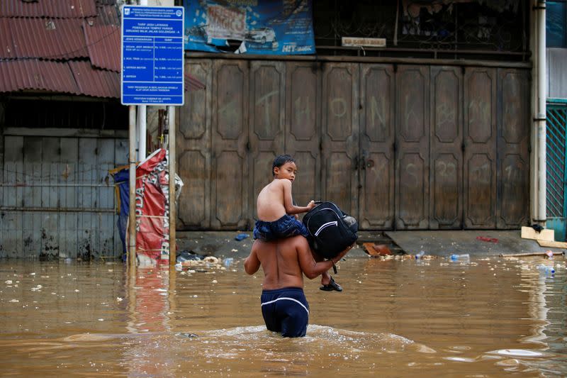 A boy is carried accross floodwaters at the Jatinegara area after heavy rains in Jakarta