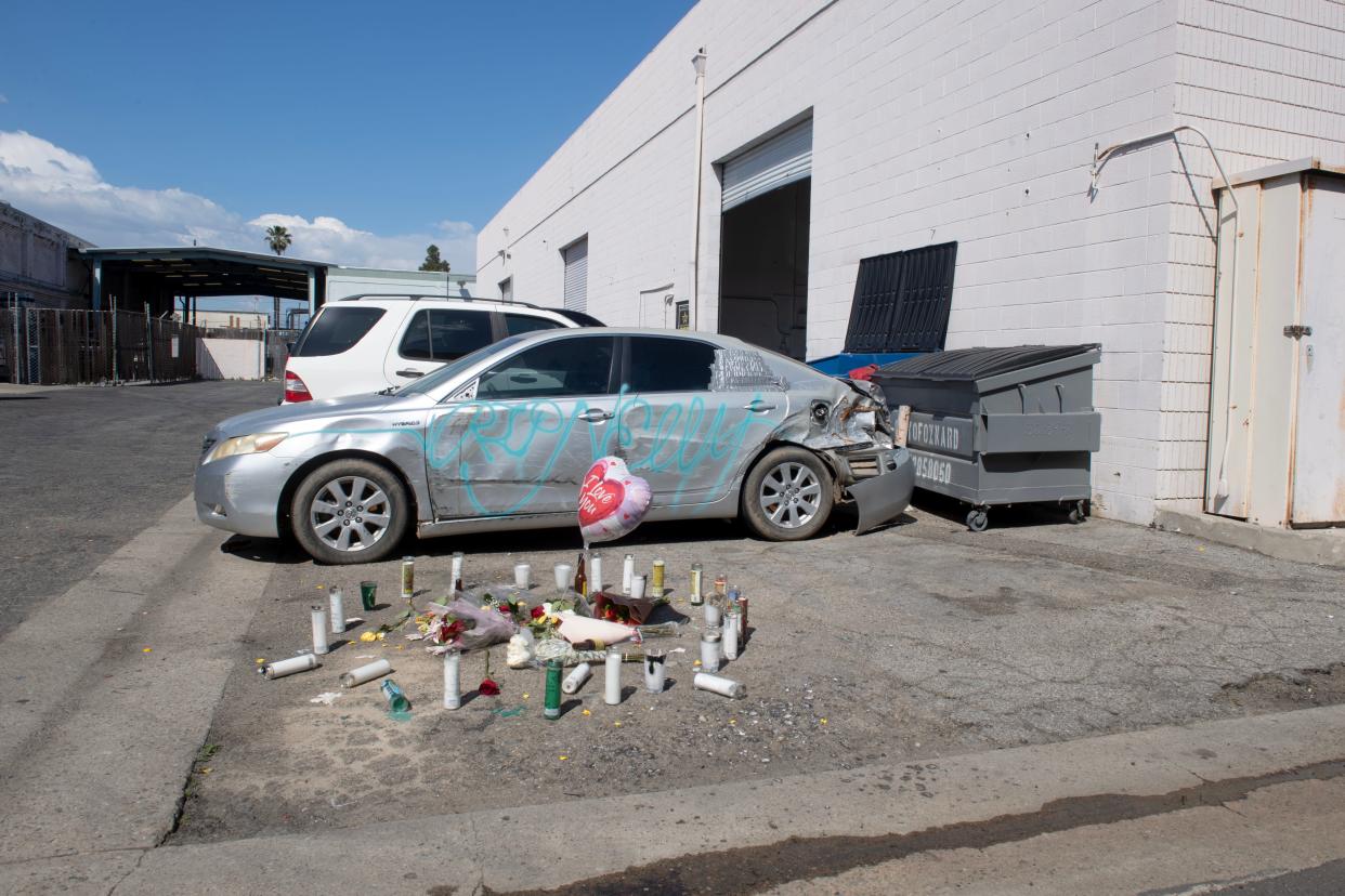 Flowers and candles sit in a circle behind a local auto body shop on Industrial Avenue in Oxnard two days after an Oxnard woman was found with a fatal gunshot wound on March 17. Two defendants have been charged with murder and kidnapping.