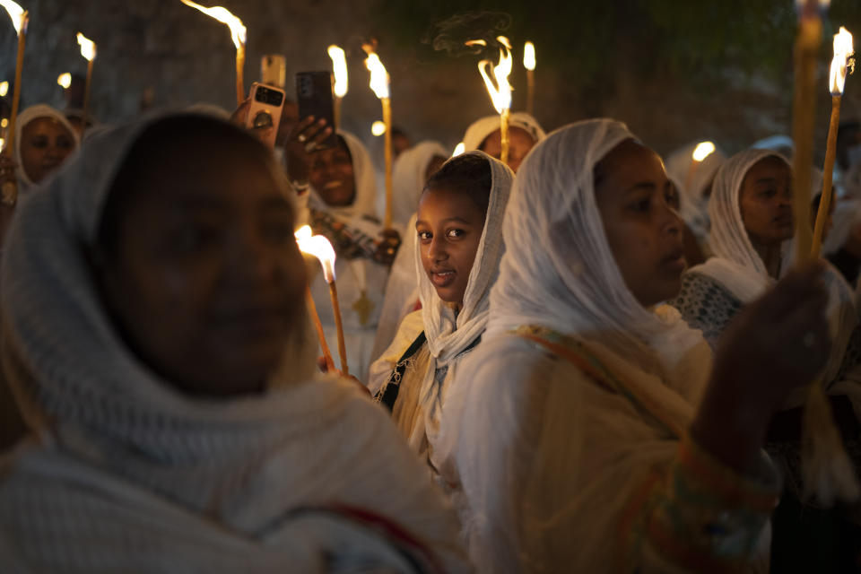 An Ethiopian Orthodox Christian pilgrim, looks at the camera as she holds a candle during the procession of the Holy Fire, at the Ethiopian monks' village Deir Al-Sultan, in the Old City of Jerusalem, Saturday, May 4, 2024. (AP Photo/Leo Correa)