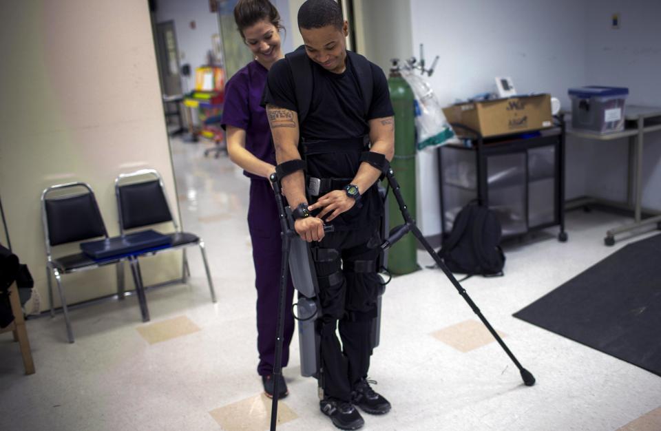 Samuels engages ReWalk electric powered exoskeletal suit by pressing a command on a wireless wrist band controller during a therapy session with Voigt, a clinical research coordinator, at the Mount Sinai Medical Center in New York City