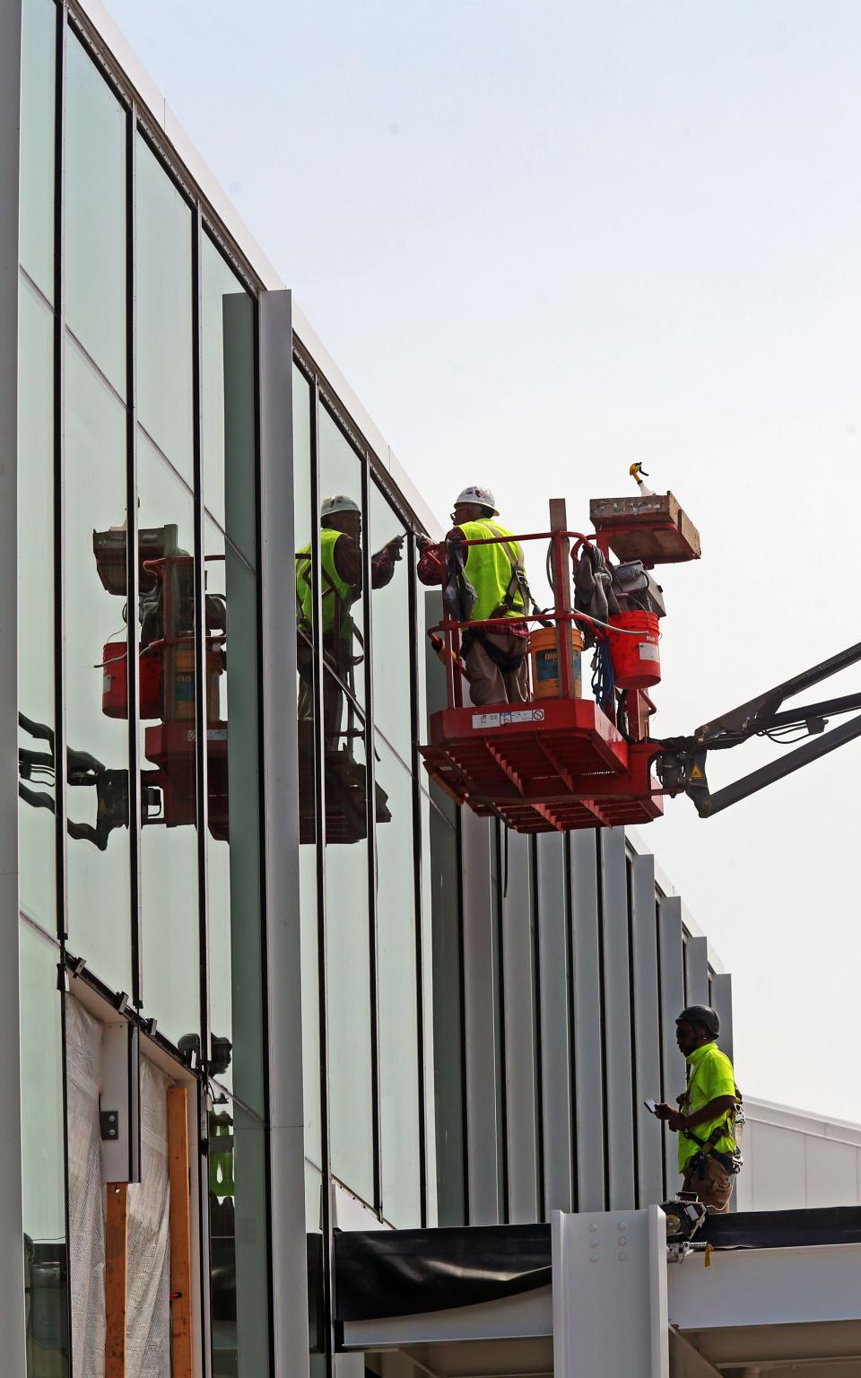 A construction crew works on the glass exterior of the future corporate campus of Komatsu Mining Corp. at 401 E. Greenfield Ave. in May 2021.