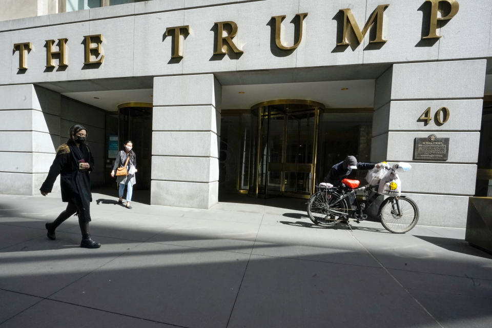 FILE - Pedestrians and a food delivery man are seen outside the Trump building on Wall Street, in New York's Financial District, on March 23, 2021. New York's attorney general sued former President Donald Trump and his company, on Wednesday, Sept. 21, 2022, alleging business fraud involving some of their most prized assets, including properties in Manhattan, Chicago and Washington, D.C. (AP Photo/Mary Altaffer, File )
