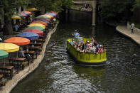 A barge tours along the Riverwalk, Friday, June 17, 2022, in San Antonio. The summer of 2022 can feel as if the coronavirus pandemic is really over. Mask rules and testing requirements are lifting in many countries, including the United States. (AP Photo/Eric Gay)