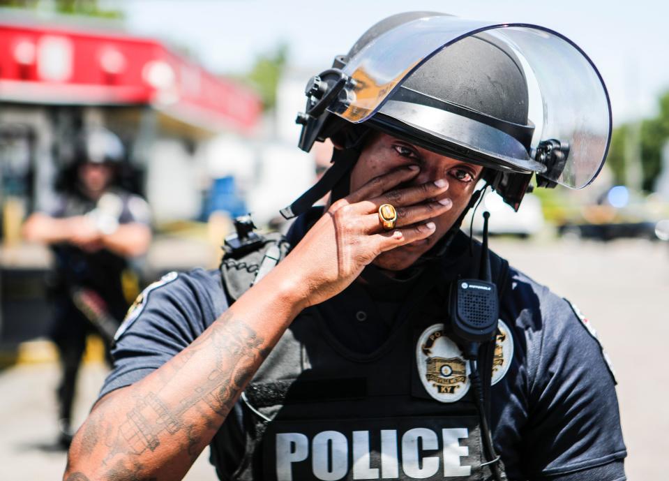 LMPD officer Christian Lewis wipes tears away after hugging a few citizens as hundreds gathered to protest the death of David McAtee, a beloved BBQ owner who shot and killed amid gunfire by LMPD and Kentucky National Guard early Monday morning near 26th and Broadway in West Louisville. June 1, 2020