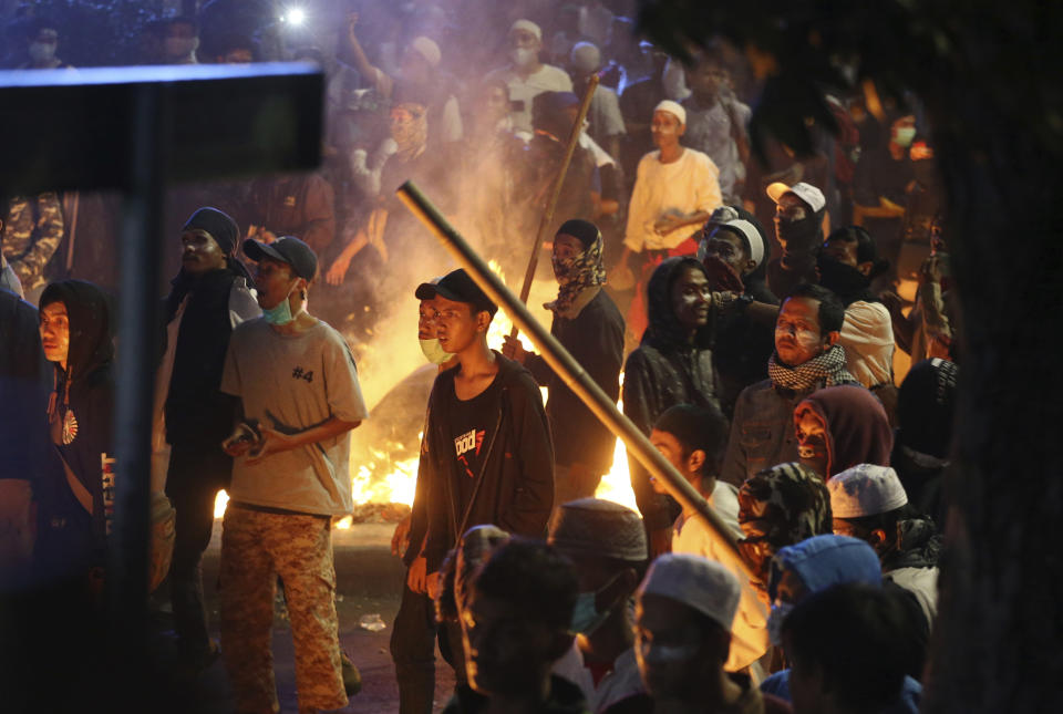 Supporters of the losing presidential candidate stand near a fire during clashes with police in Jakarta, Indonesia, Wednesday, May 22, 2019. Indonesian President Joko Widodo said authorities have the volatile situation in the country's capital under control after a number of people died Wednesday in riots by supporters of his losing rival in last month's presidential election. (AP Photo/Achmad Ibrahim)