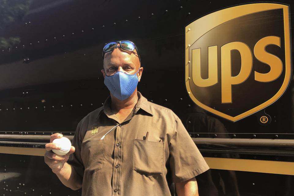 UPS driver Derek Reynolds poses with a foul ball gift, Friday, Sept. 18, 2020, in Alameda, Calif. (AP Photo/Janie McCauley)