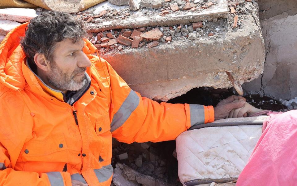 Mesut Hancer holds the hand of his 15-year-old daughter Irmak, who died in the earthquake in Kahramanmaras, close to the quake's epicentre, the day after a 7.8-magnitude earthquake struck the country's southeast - AFP