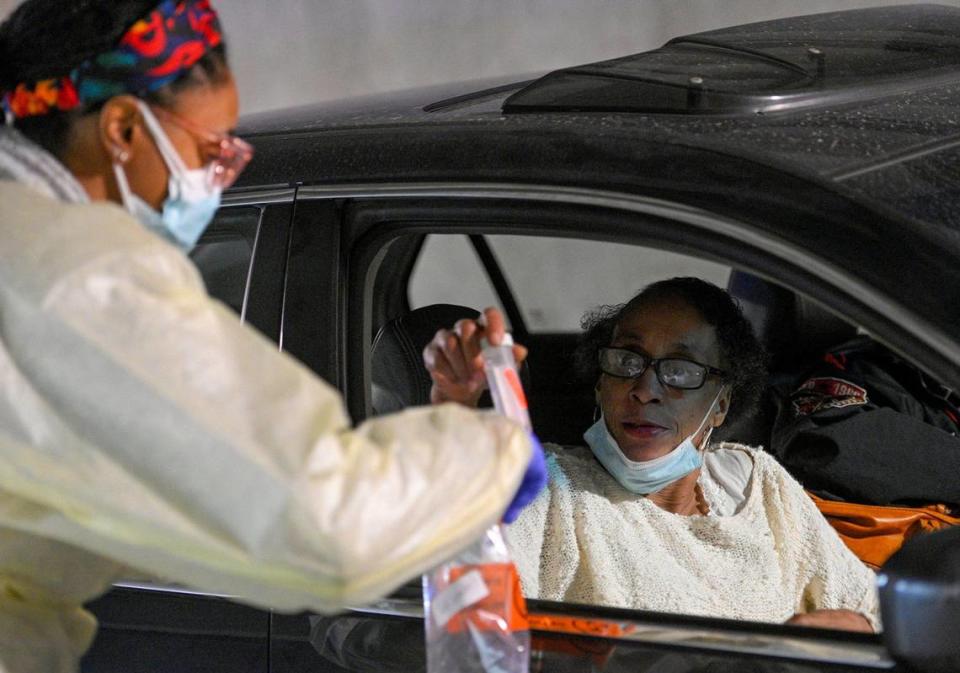 Theresa Harstad of Kansas City, right, hands her sample to registered nurse Brea Lewis at the University Health COVID drive-thru testing location on Friday.