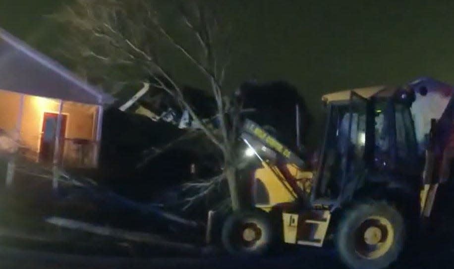 A tree blocks a backhoe from hitting a Vineland home after police shot the machine's operator on Dec. 18, 2021.