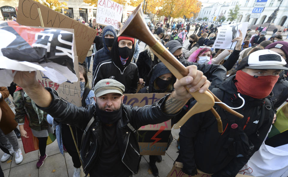 Demonstrators wear protective face masks during a protest a church where they were protesting church support for tightening Poland's already restrictive abortion law in Warsaw, Poland, Sunday, Oct. 25, 2020. Poland constitutional court issued a ruling on Thursday that further restricts abortion rights in Poland, triggering four straight days of protests across Poland.(AP Photo/Czarek Sokolowski)