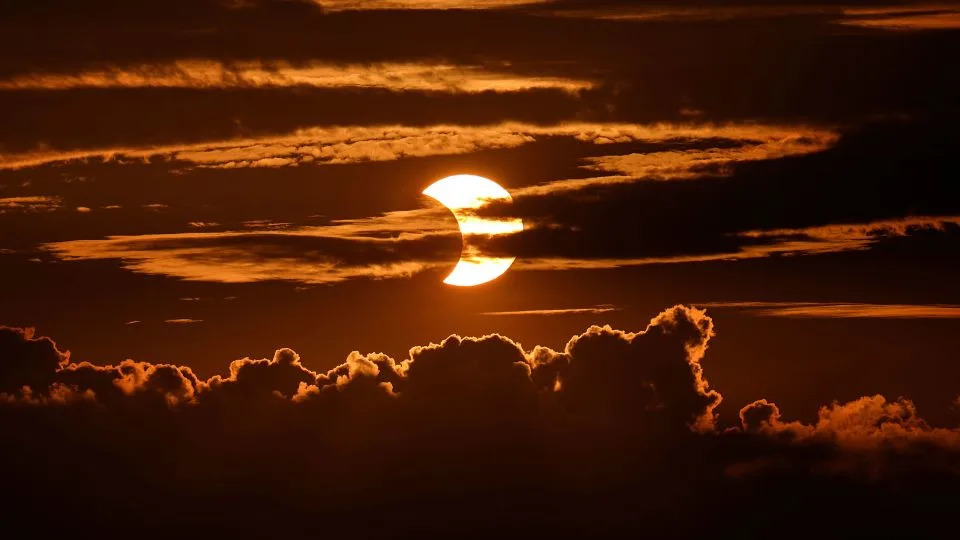 High-level clouds are seen at the top of the image as a partial solar eclipse unfolds behind clouds, Thursday, June 10, 2021, in Arbutus, Maryland. - Julio Cortez/AP