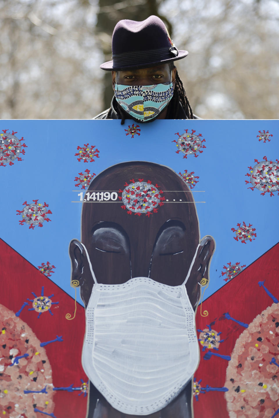 In this Tuesday, April 21, 2020 photo, Obi Uwakwe poses with his painting in Chicago. Uwakwe is an artist/photographer and submitted his art work to the the Illinois State Museum, which is documenting what daily life is like for Illinois families during the coronavirus pandemic. (AP Photo/Nam Y. Huh)