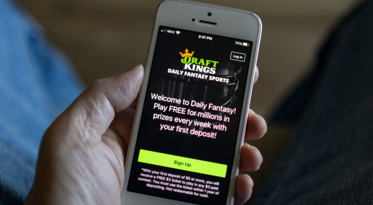 A man opens the DraftKings (DKNG) app from his iPhone. DraftKings is an American daily fantasy sports contest and sports betting operator. DKNG Stock Forecast