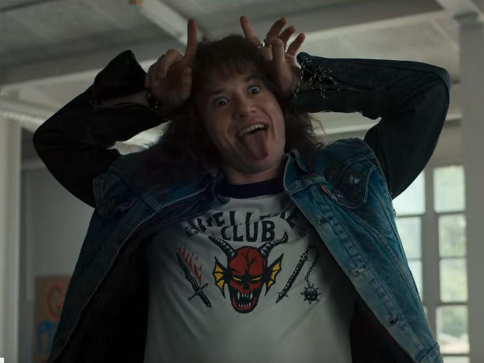 joseph quinn as eddie munson in stranger things, sticking out his tongue, placing his hands on his head like horns, and making a silly face