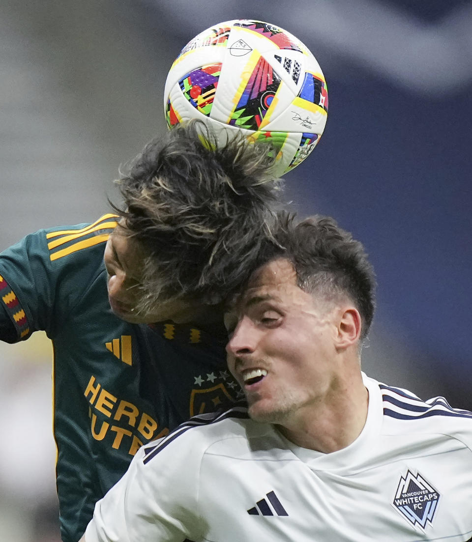 LA Galaxy's Miki Yamane, left, and Vancouver Whitecaps' Alessandro Schopf collide while vying for the ball during the first half of an MLS soccer match Saturday, April 13, 2024, in Vancouver, British Columbia. (Darryl Dyck/The Canadian Press via AP)