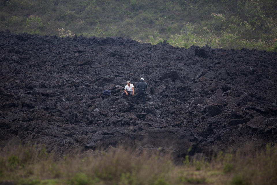 Men chat amid a band of harden lava that flowed from the Pacaya Volcano, near El Patrocinio village in San Vicente Pacaya, Guatemala, Wednesday, April 21, 2021. The 8,373-foot volcano, just 30 miles south of Guatemala’s capital, has been active since early February. (AP Photo/Moises Castillo)