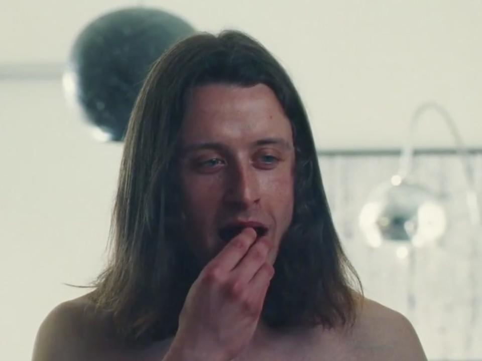 Rory Culkin stands naked while eating strawberries and looking at Dre (Dominique Fishback).