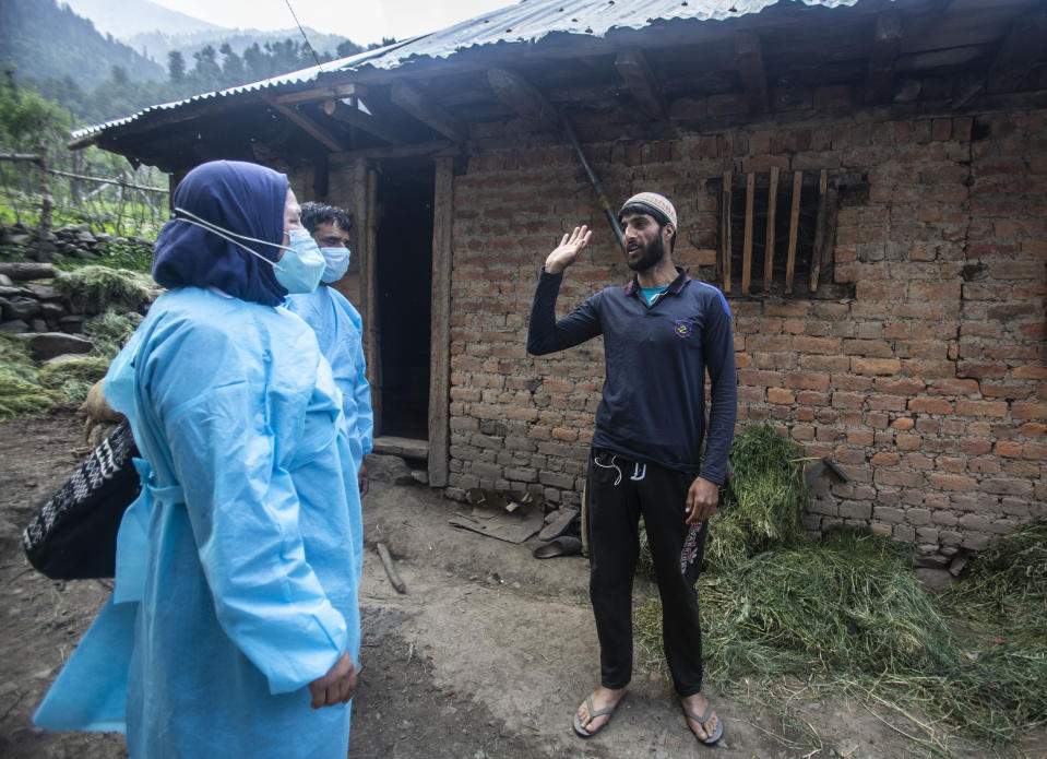 Health workers talk to Bilal Chauhan, a local villager, to persuade him to take the COVID-19 vaccine in Minnar village, north of Srinagar, Indian controlled Kashmir, Thursday, June 10, 2021. Chauhan and many other villagers refused to take vaccine saying the were from the mountains and too hardy to be affected by the virus. (AP Photo/Mukhtar Khan)