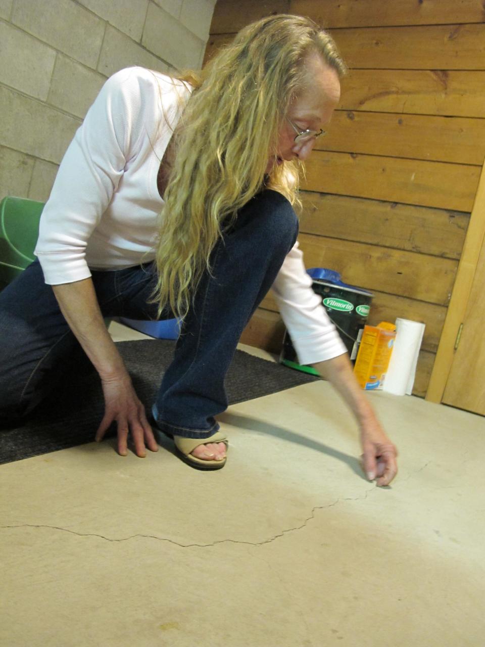 Sharon Binger points to a crack on Wednesday, March 21, 2012 in the basement of her home in Clintonville, Wis. Binger said it was caused by vibrations and booms that city officials are unable to explain. Sleepless families in the small Wisconsin town longed for quiet Wednesday after mysterious booming noises over the past few nights roused them from bed and sent residents into the street — sometimes still in pajamas. (AP Photo/Carrie Antlfinger)