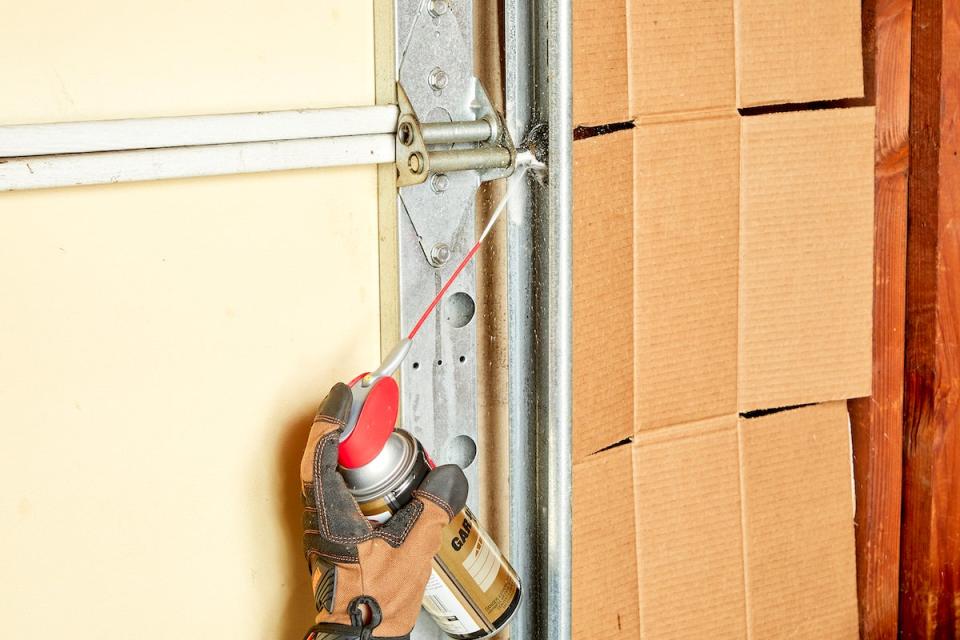 Woman lubricating garage door rollers.