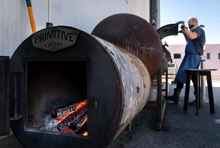Tropical Smokehouse executive chef and co-owner Rick Mace works his custom-built smoker at the months-old barbecue restaurant he opened on South Dixie Highway in West Palm Beach.