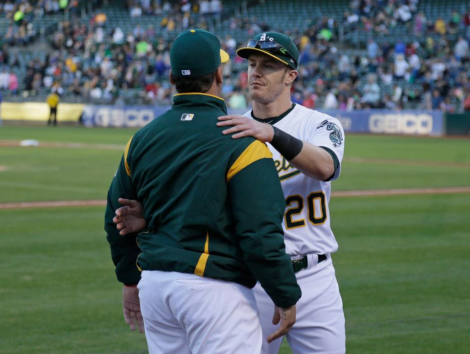 Oakland Athletics catcher Bruce Maxwell, left, is embraced by teammate Mark Canha, right, after Maxwell knelt for the national anthem before the start of a baseball game against the Texas Rangers Saturday, Sept. 23, 2017, in Oakland, Calif. (AP Photo/Eric Risberg)