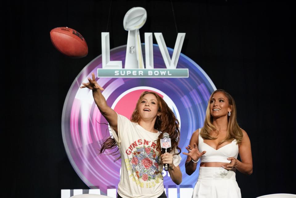 NFL Super Bowl 54 football game halftime performer Jennifer Lopez and Shakira throws a football at a news conference Thursday, Jan. 30, 2020, in Miami. (AP Photo/Morry Gash)
