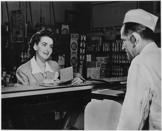 During World War II, a wife and mother presents her ration book to the butcher behind the counter of a deli, Hyde Park, New York, 1943. (Photo: Smith Collection/Gado via Getty Images)