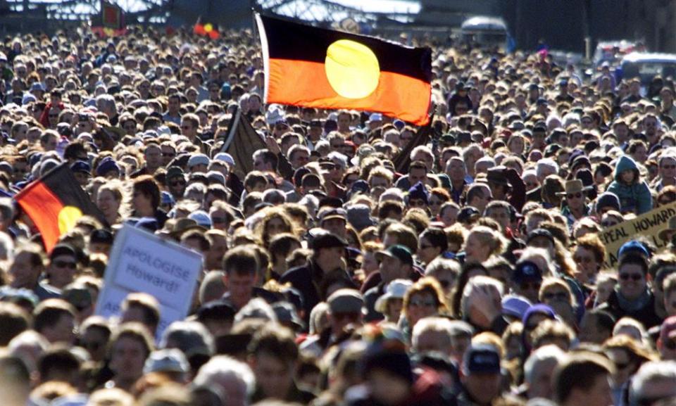 Aboriginal flags rise above a crowd walking across Sydney Harbour Bridge in 2000.