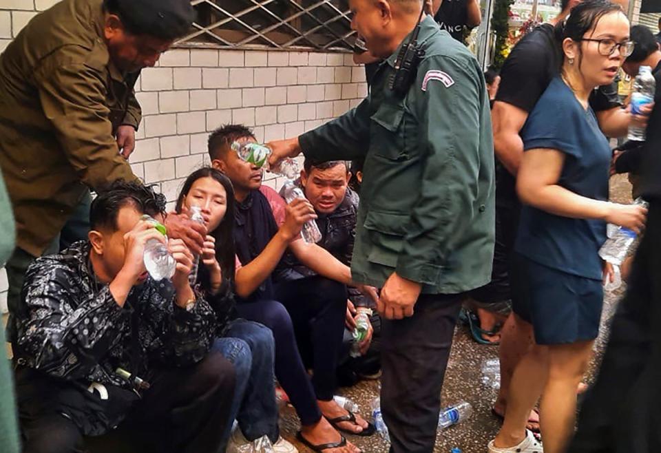 In this photo provided by Cambodia's Fresh News, victims of a fire receive water from police officers (AP)