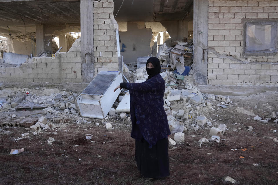 Ayesha stands in front of her home, which was destroyed in the devastating earthquake, in Atareb, Syria, Sunday, Feb. 12, 2023. “When I look at our house, I wonder how did anyone come out alive?” Ayesha said. “Maybe it would have been better if I died. I came from under that rubble carrying the rubble of the whole world on my shoulders.” (AP Photo/Hussein Malla)