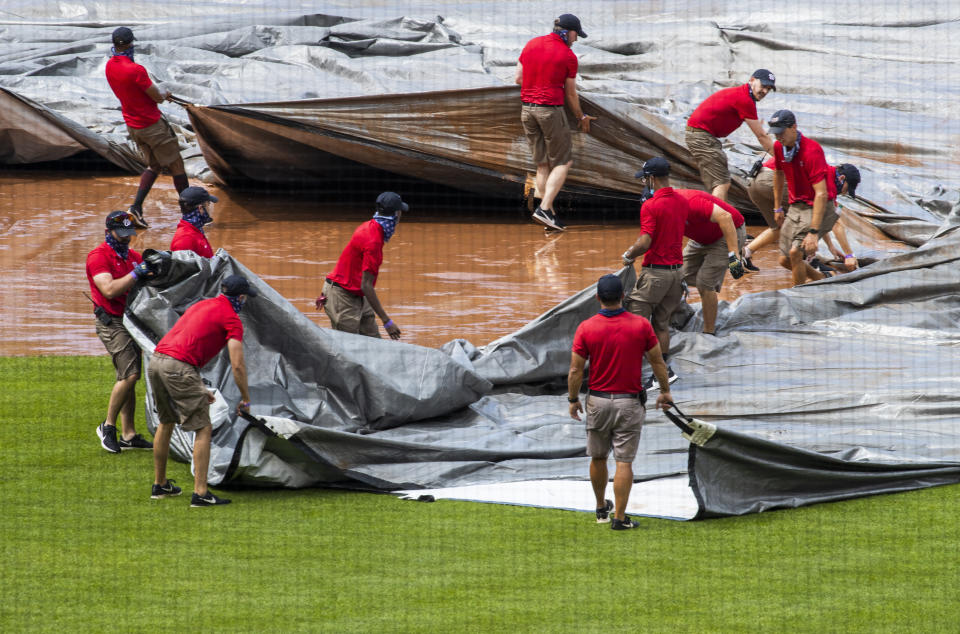 Grounds crew tries to untangle the tarp as they attempt to cover the baseball diamond from a heavy downpour delaying the baseball game during the sixth inning of a baseball game between the Washington Nationals and the Baltimore Orioles in Washington, Sunday, Aug. 9, 2020. (AP Photo/Manuel Balce Ceneta)