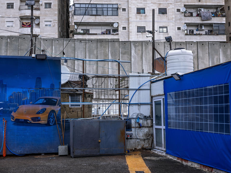 FILE - A car wash station located next to Israel's separation barrier with Shuafat refugee camp behind it, in Jerusalem, Feb. 6, 2022. (AP Photo/Oded Balilty, File)