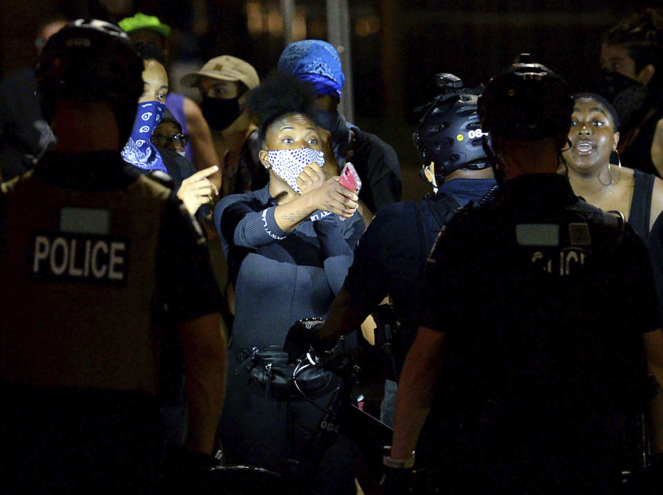 Two protesters express their opinions to Charlotte Mecklenburg Police bike officers at the intersection of South Caldwell Street and Stonewall Street in uptown Charlotte, N.C., on Friday, Aug. 21, 2020. (Jeff Siner/The Charlotte Observer via AP)