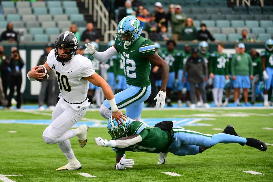 Nov 12, 2022; New Orleans, Louisiana, USA; UCF Knights quarterback John Rhys Plumlee (10) runs the ball past Tulane Green Wave defensive back Jarius Monroe (11) and Tulane Green Wave safety Bailey Despanie (32) during the first quarter at Yulman Stadium. Mandatory Credit: Rebecca Warren-USA TODAY Sports