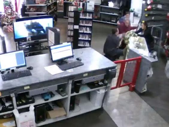 Still image from CCTV footage shows store manager Bill Reel catching a baby as it falls off a shop counter while two women look at a gun in Family Pawn in Utah, US. (Bill Reel)