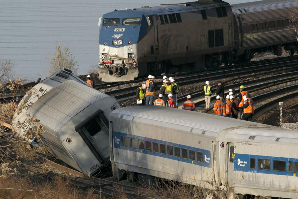 FILE - In this Dec. 1, 2013 file photo, an Amtrak train, top, traveling on an unaffected track, passes a derailed Metro North commuter train in the Bronx borough of New York. Senators say they’re frustrated with the government’s slow pace at writing new rail safety regulations in light of recent fiery freight train accidents and a deadly commuter train derailment. Sen. Richard Blumenthal, D-Conn., warned witnesses at a Senate hearing Thursday, “one of the things we're going to do here is impose accountability”. (AP Photo/Mark Lennihan, File)