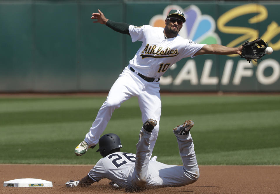 New York Yankees' Andrew McCutchen, bottom, steals second base as Oakland Athletics shortstop Marcus Semien reaches for a throw by catcher Jonathan Lucroy, who was charged with a throwing error, during the first inning of a baseball game in Oakland, Calif., Monday, Sept. 3, 2018. (AP Photo/Jeff Chiu)