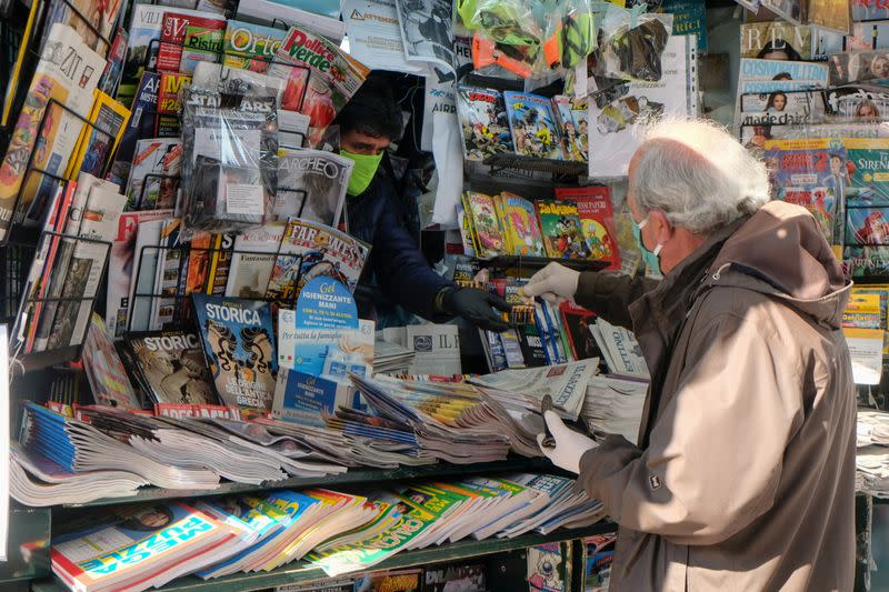 FILE PHOTO: A man wears a protective face mask and gloves at the newsstand as the Italian government allows the reopening of some shops while a nationwide lockdown continues following the outbreak of the coronavirus disease (COVID-19) in Venice