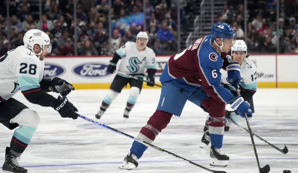 Colorado Avalanche defenseman Erik Johnson, front right, collects the puck as Seattle Kraken defenseman Carson Soucy, left, and left wing Brandon Tanev pursue during the third period of an NHL hockey game Friday, Oct. 21, 2022, in Denver. (AP Photo/David Zalubowski)