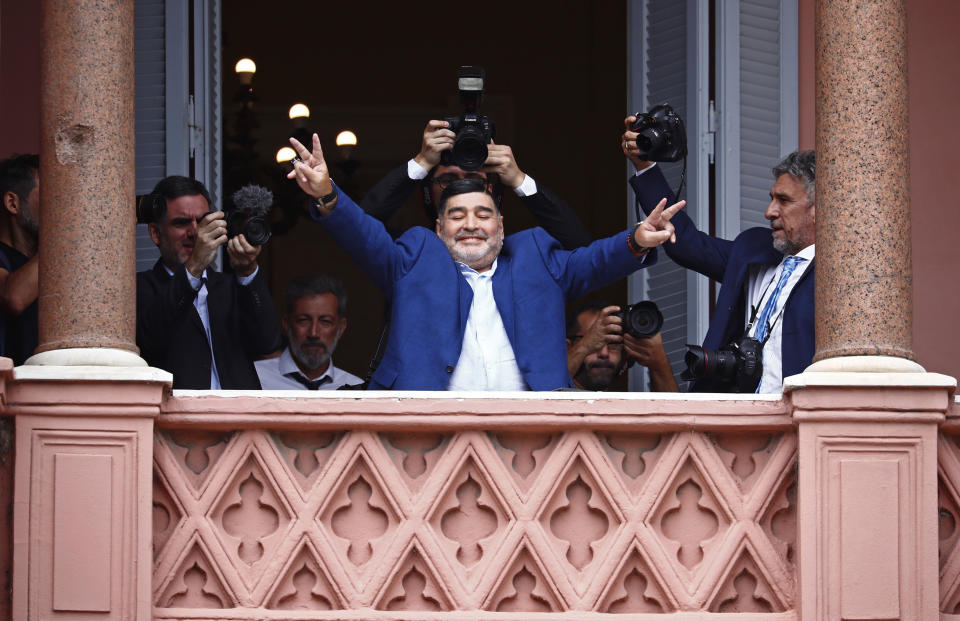 FILE - In this Dec. 26, 2019 file photo, former soccer great Diego Maradona flashes victory signs to fans below at the Casa Rosada government house after meeting with Argentine President Alberto Fernandez in Buenos Aires, Argentina. Decades ago, Maradona held up his team's soccer trophy at this spot on the balcony after winning the World Cup in Mexico in 1986. The Argentine soccer great who was among the best players ever and who led his country to the 1986 World Cup title before later struggling with cocaine use and obesity, died from a heart attack on Wednesday, Nov. 25, 2020, at his home in Buenos Aires. He was 60. (AP Photo/Marcos Brindicci, File)