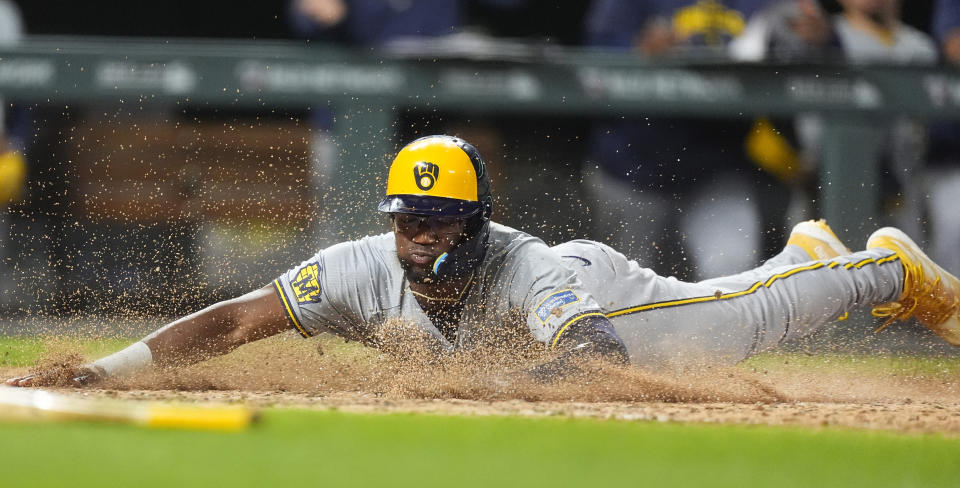 Milwaukee Brewers' Andruw Monasterio slides across home plate to score the tying run on a sacrifice fly hit by Willy Adames off Colorado Rockies relief pitcher Nick Mears in the ninth inning of a baseball game Tuesday, July 2, 2024, in Denver. (AP Photo/David Zalubowski)