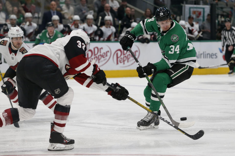 Arizona Coyotes defenseman Alex Goligoski (33) and Dallas Stars right wing Denis Gurianov (34) reach for the puck during the first period of an NHL hockey game in Dallas, Wednesday, Feb. 19, 2019. (AP Photo/Michael Ainsworth)